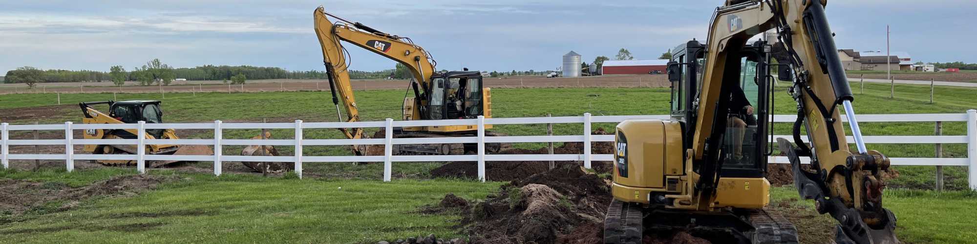2 backhoes and a skid steer working on a farm field